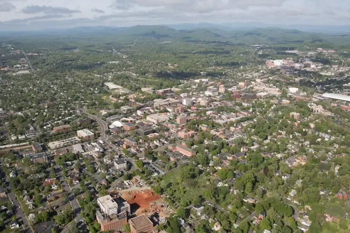 Aerial view of a sprawling cityscape with dense green trees and residential buildings.