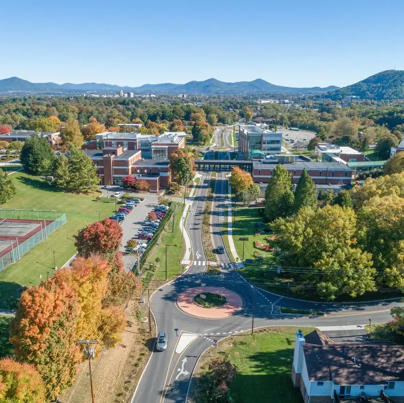 Aerial view of a suburban area with vibrant autumn foliage and a roundabout.